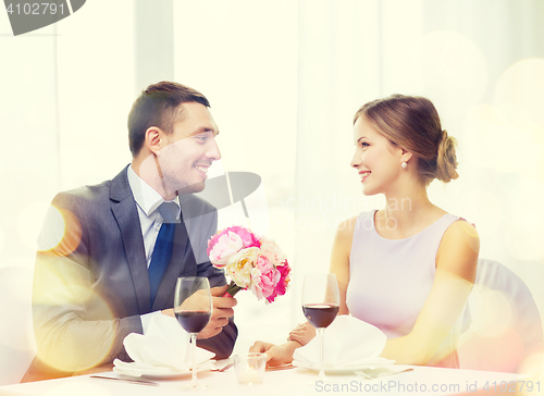 Image of smiling man giving flower bouquet at restaurant