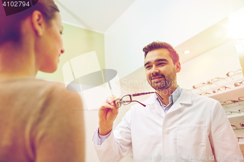 Image of optician giving glasses to woman at optics store