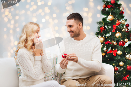 Image of man giving woman engagement ring for christmas