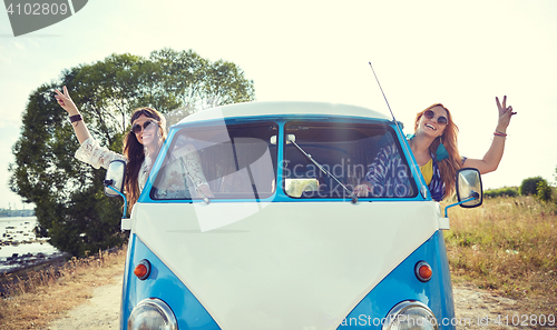 Image of smiling young hippie women driving minivan car