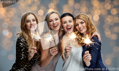 Image of happy young women with sparklers over lights