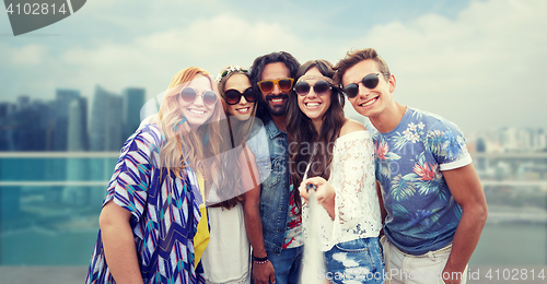 Image of happy hippie friends with selfie stick over city