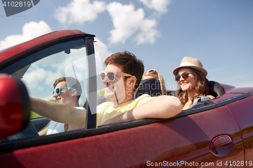 Image of happy friends driving in cabriolet car