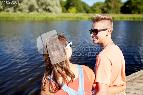 Image of happy teenage couple sitting on river berth