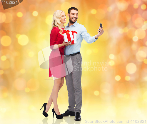 Image of happy couple with smartphone and gift boxes