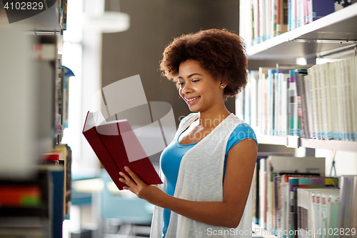 Image of happy african student girl reading book at library