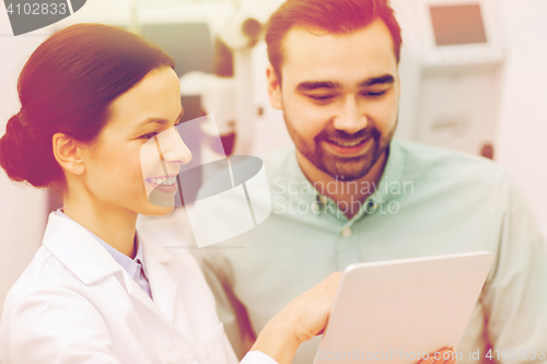 Image of optician with tablet pc and patient at eye clinic