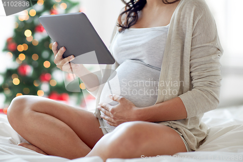 Image of close up of pregnant woman with tablet pc at home