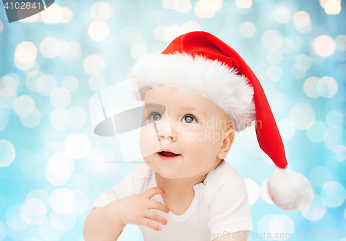 Image of baby boy in christmas santa hat over blue lights