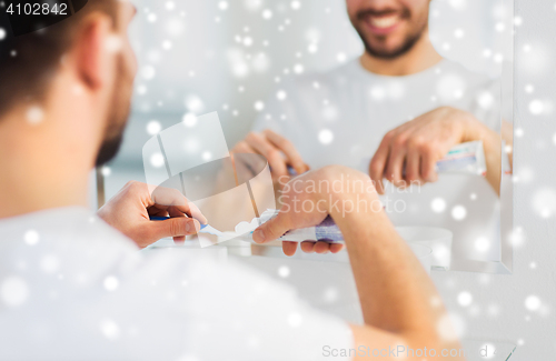 Image of close up of man squeezing toothpaste on toothbrush