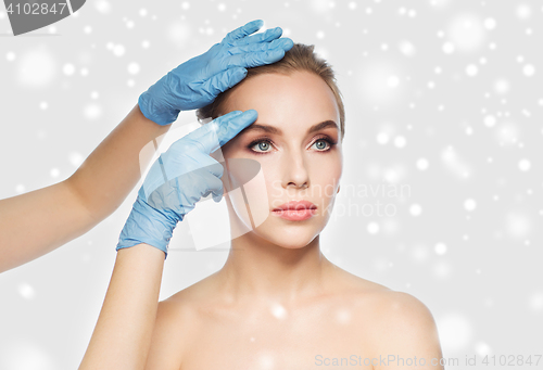 Image of surgeon or beautician hands touching woman face