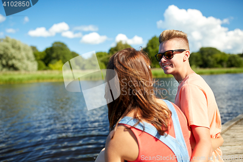 Image of happy teenage couple sitting on river berth