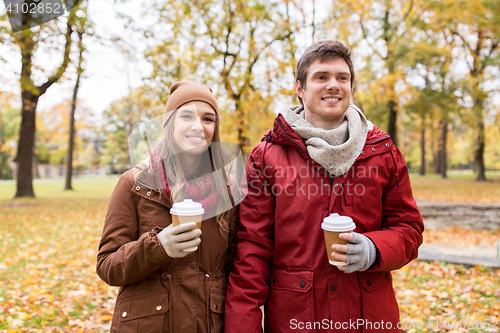 Image of happy couple with coffee walking in autumn park