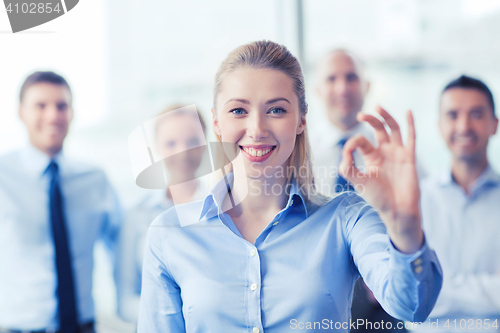 Image of smiling businesswoman showing ok sign in office