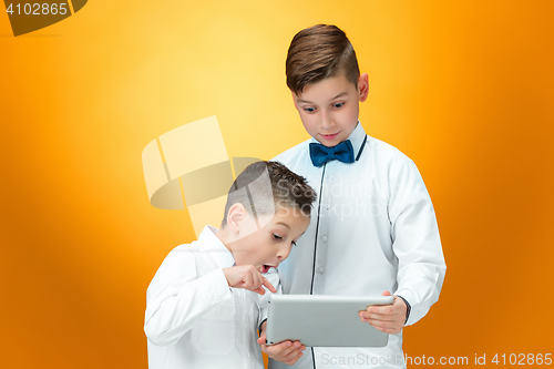 Image of The two boys using laptop on orange background