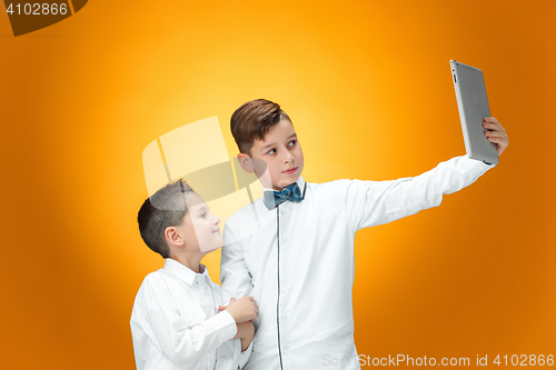 Image of The two boys using laptop on orange background