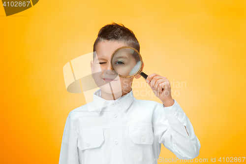 Image of Little boy using magnifier looking close up