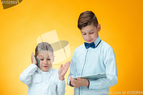 Image of The two boys using laptop on orange background