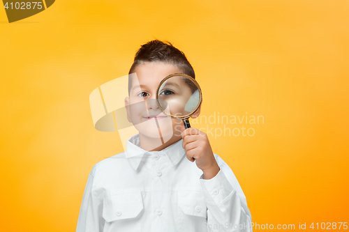 Image of Little boy using magnifier looking close up