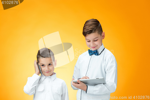 Image of The two boys using laptop on orange background