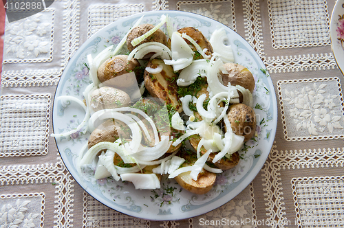 Image of Russian Traditional baked potatoes with the peel, onion and fennel, drizzled oil on a plate gray ornament