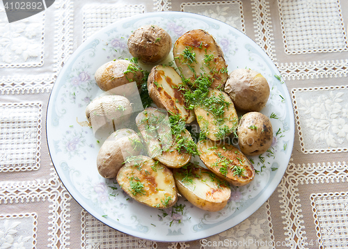 Image of Russian Traditional baked potatoes with the peel and fennel, drizzled  oil on a plate   gray ornament