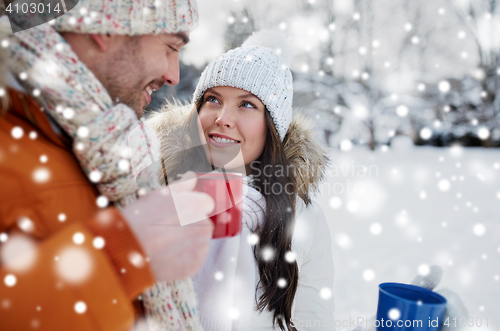 Image of happy couple with tea cups over winter landscape