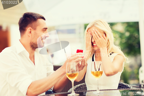 Image of happy couple with engagement ring and wine at cafe