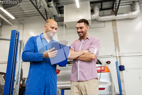 Image of auto mechanic with clipboard and man at car shop