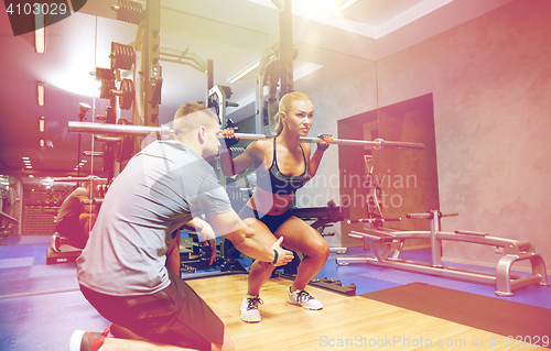 Image of man and woman with bar flexing muscles in gym