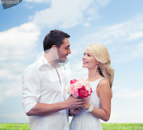 Image of happy couple with flowers over natural background
