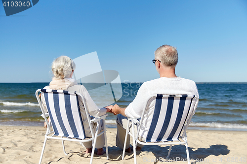 Image of senior couple sitting on chairs at summer beach