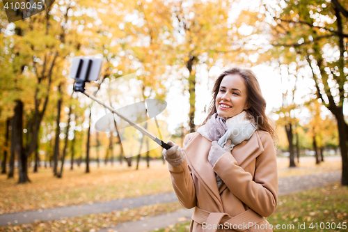 Image of woman taking selfie by smartphone in autumn park