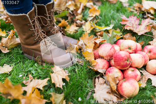 Image of woman feet in boots with apples and autumn leaves