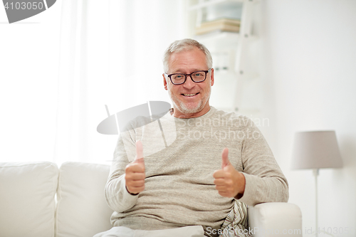 Image of smiling senior man showing thumbs up at home