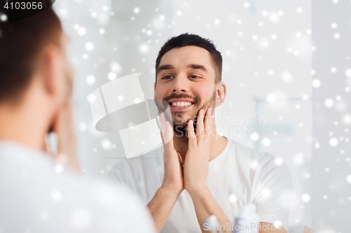 Image of happy young man looking to mirror at home bathroom