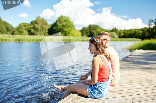 Image of happy teenage couple sitting on river berth