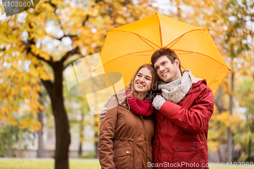 Image of smiling couple with umbrella in autumn park