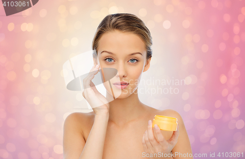 Image of young woman applying cream to her face