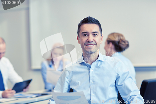 Image of smiling group of businesspeople meeting in office