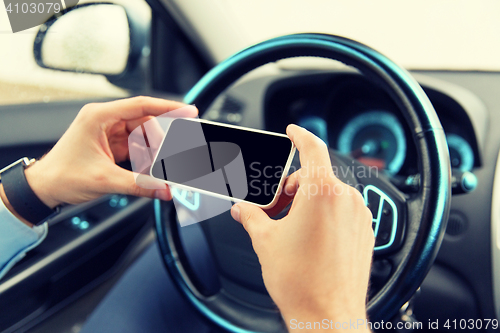 Image of close up of man hand with smartphone driving car