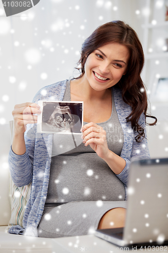 Image of happy pregnant woman with ultrasound image at home