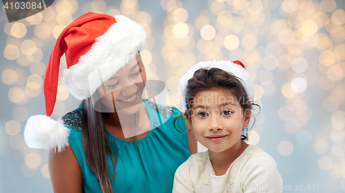 Image of happy mother and little girl in santa hats