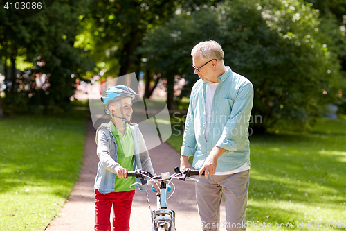 Image of grandfather and boy with bicycle at summer park