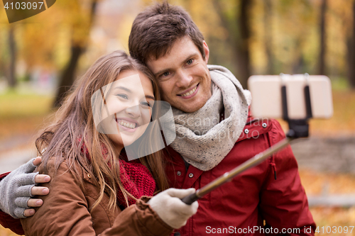 Image of couple taking selfie by smartphone in autumn park