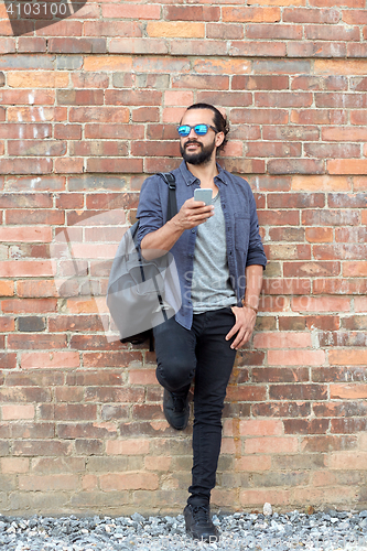 Image of happy man with backpack and smartphone on street