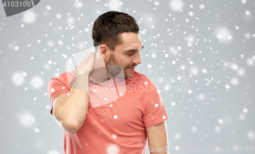 Image of unhappy man suffering from neck pain over snow
