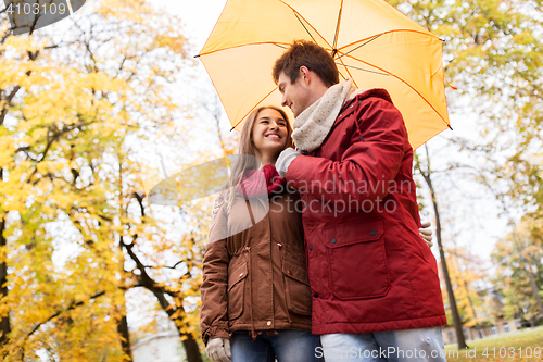 Image of smiling couple with umbrella in autumn park