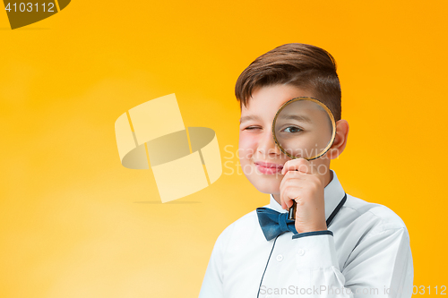 Image of Little boy using magnifier looking close up