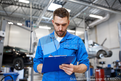 Image of auto mechanic man with clipboard at car workshop